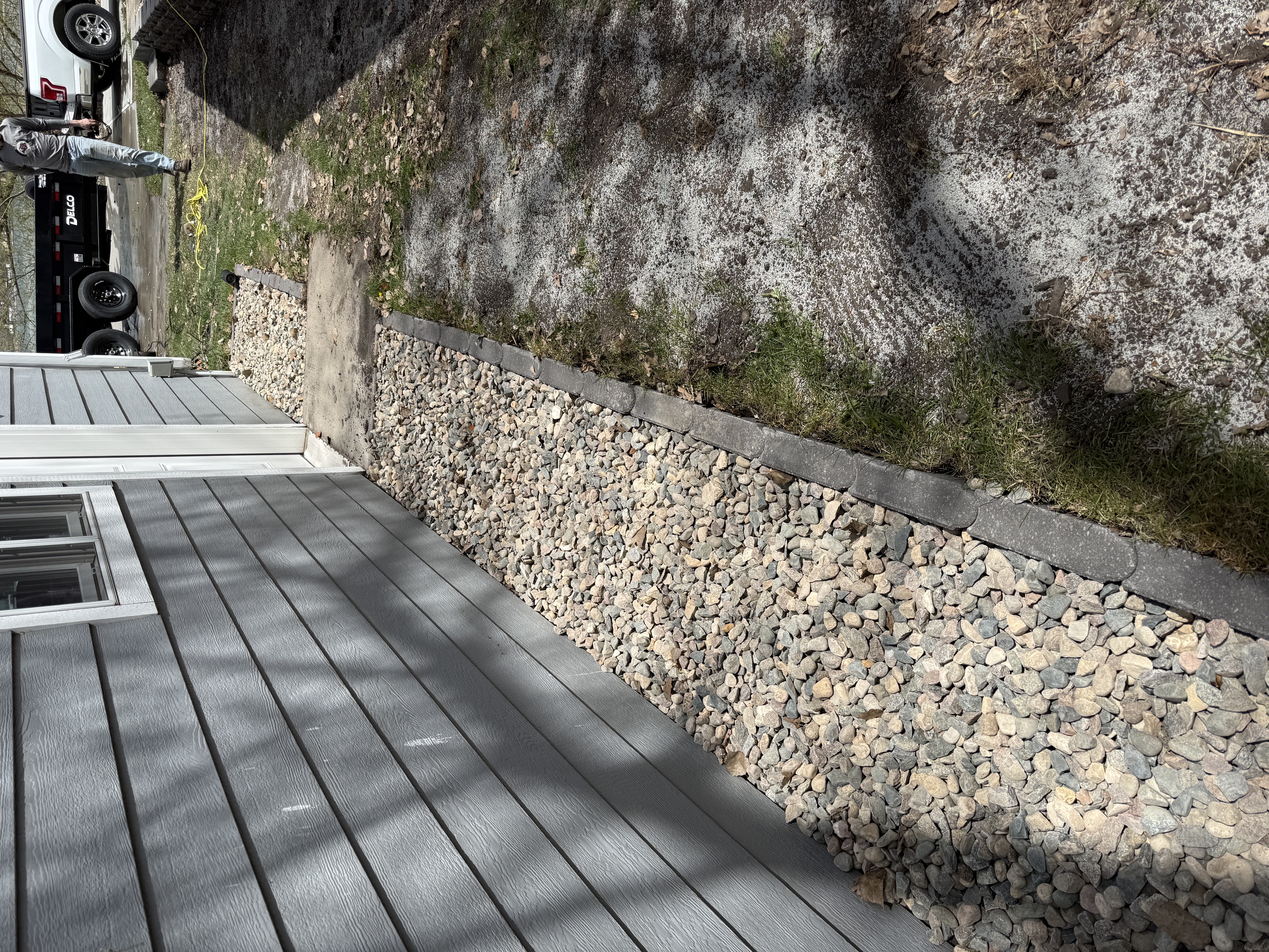 Composite decking with rock gravel border and retaining edge